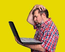 Frustrated businessman looking at his laptop computer thst has no leads to work