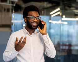 Cheerful young African-American businessman with glasses, chats on his phone with a new customer provided by R54Media's Local Lead Machine.